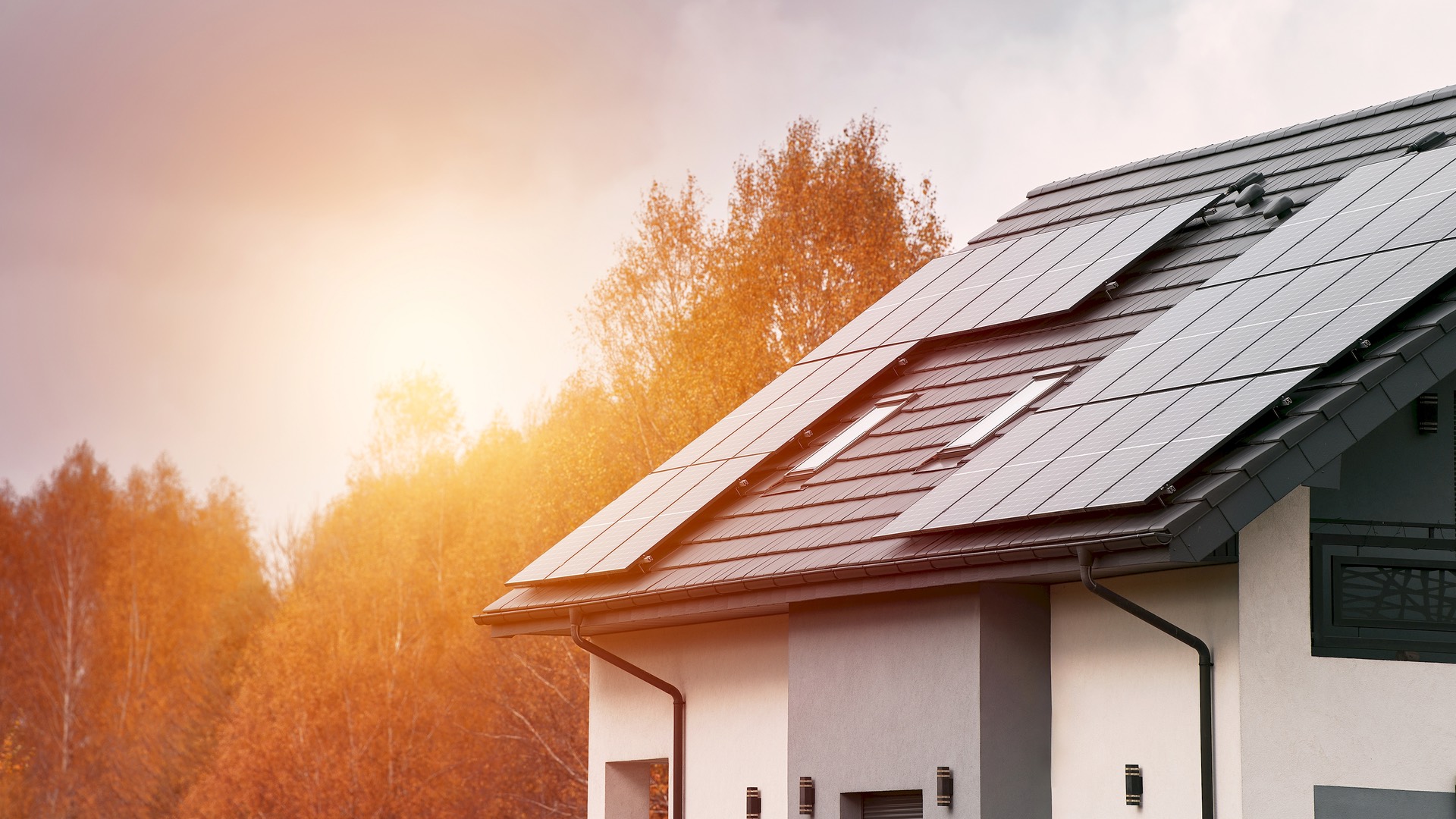 Casa moderna con pannelli fotovoltaici sul tetto, circondata dagli alberi d'autunno